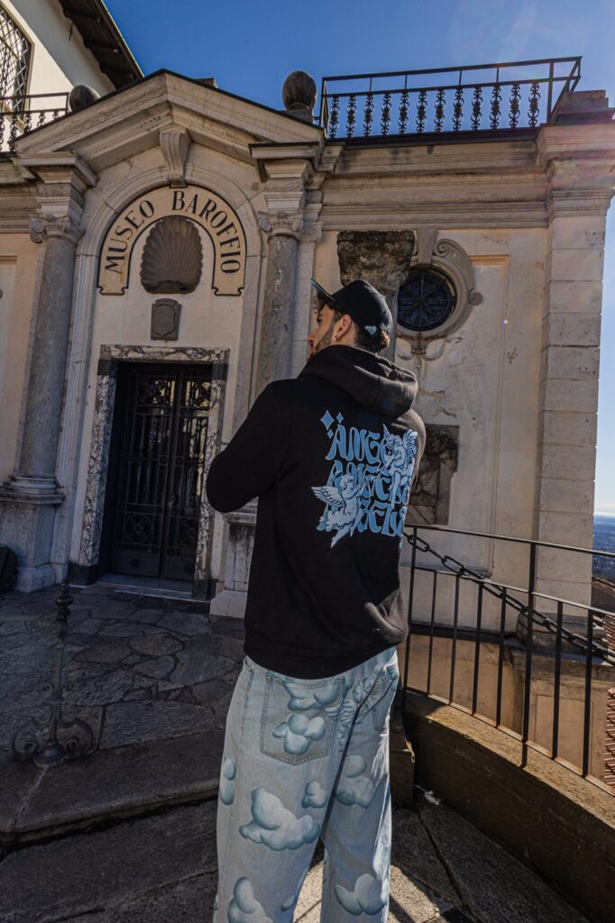 LILMINE di spalle con la felpa Angel Drop, davanti a una chiesa